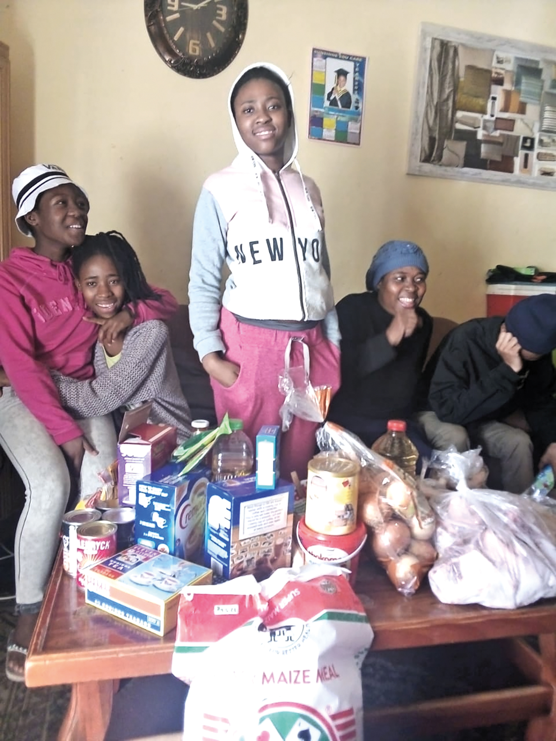 Twee HIV+ tieners en leden van de supportgroep met een voedselpakket van de Sister Mura Foundation.